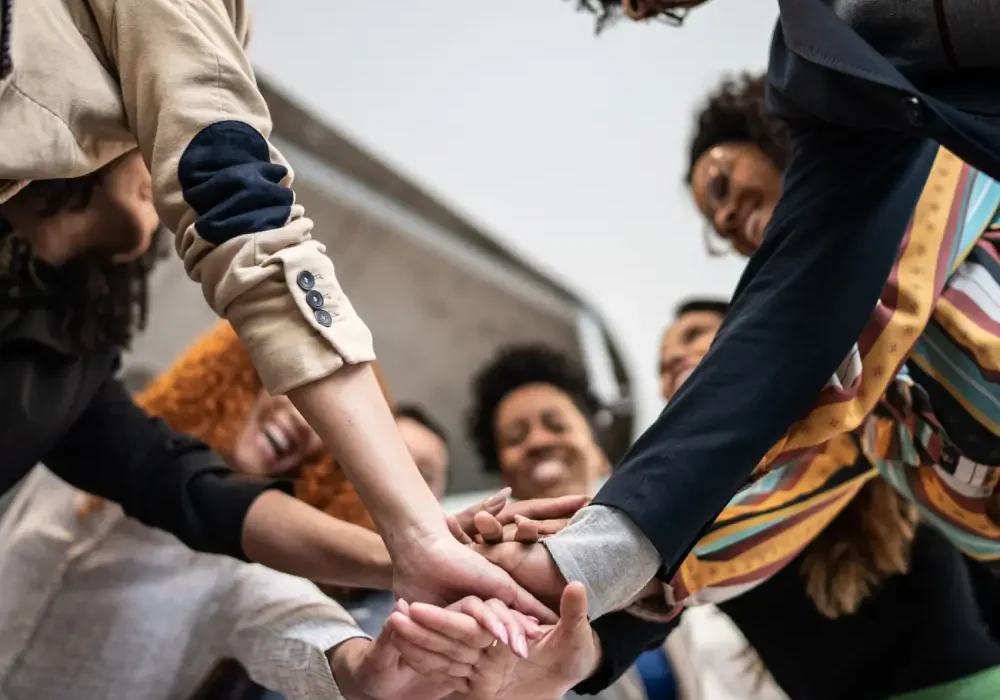 Diverse team joining hands in huddle